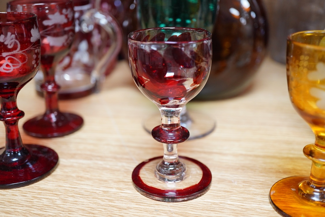 A collection of coloured glass flagons, glasses and bottles etc. (18). Tallest decanter and stopper 25cm high.